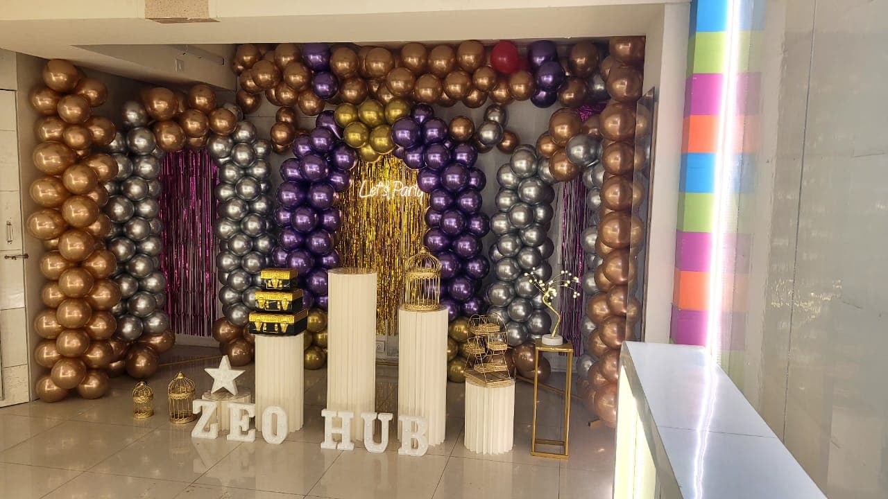 ZEO HUB marquee letters with Let's Party neon and balloon columns